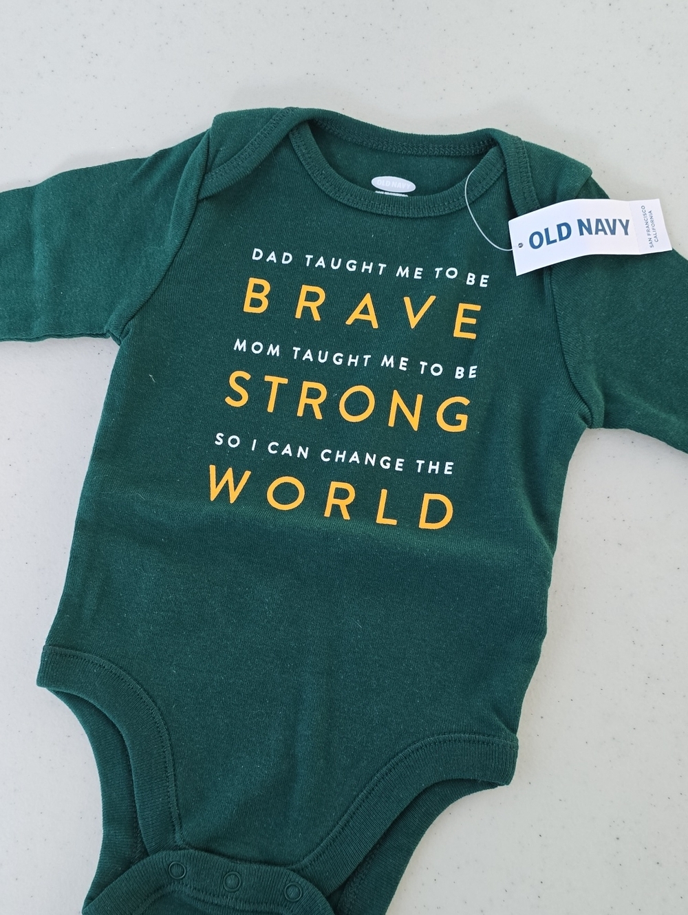 Old Navy Green Baby One-Piece with Yellow Text "Brave Strong World"